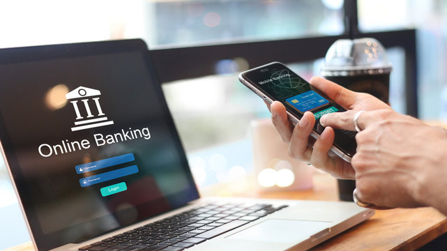 A Laptop screen showing Online Banking, with hands holding a mobile phone near the screen