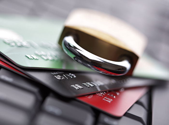 An image of a lock laying atop three credit cards on a computer keyboard, signifying security with online shopping
