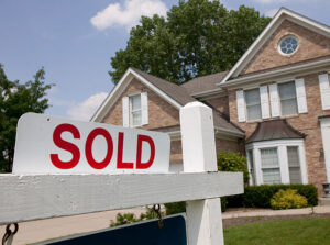 a real estate SOLD sign in front of an attractive suburban home