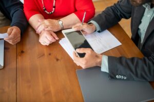 A loan officer going over documents with a couple seated at a wooden table
