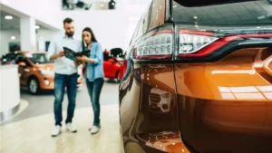 A couple in a showroom in front of a vehicle